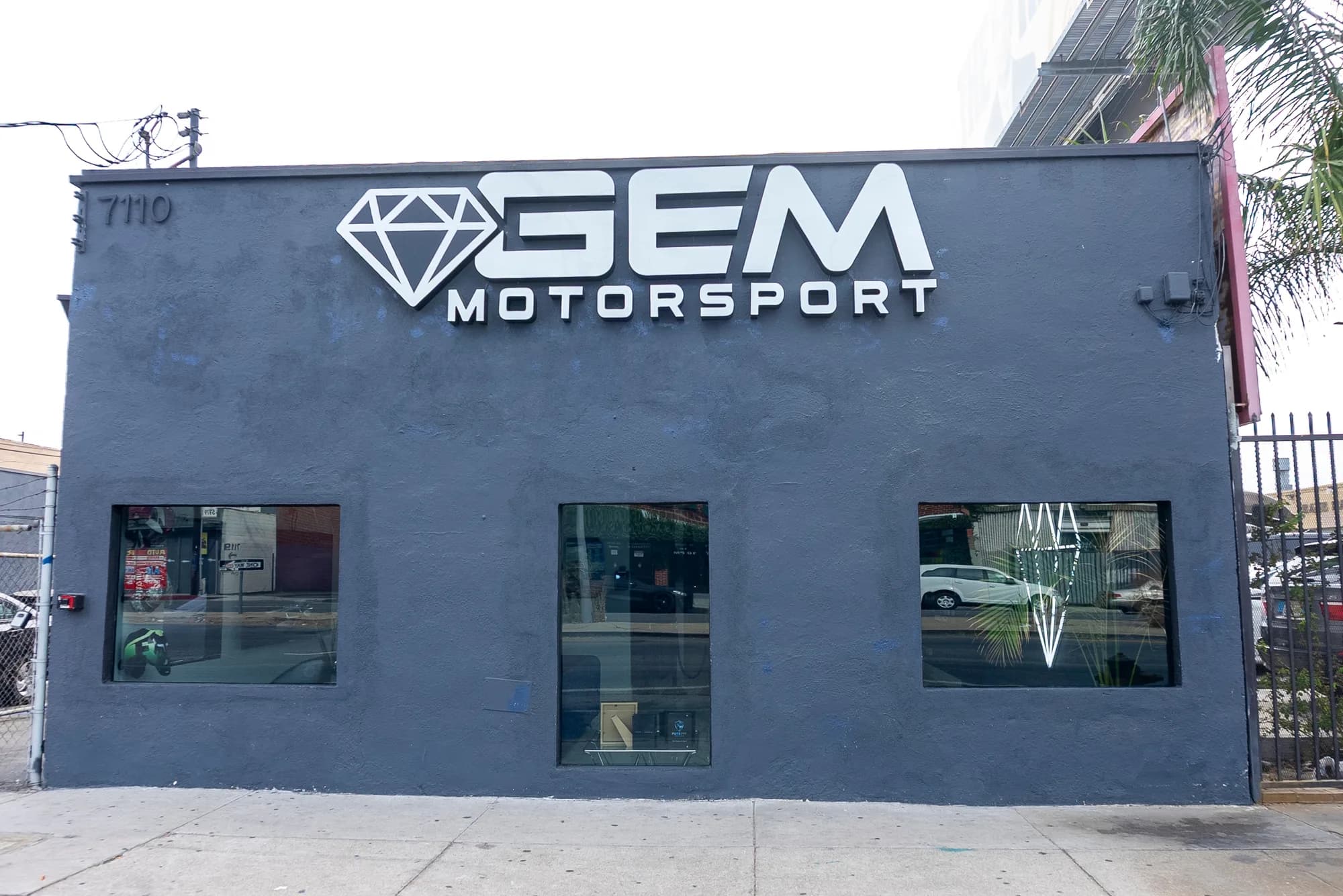 The GEM facility exterior — grey stucco building with the GEM diamond sign above three windows